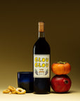 Las Jaras Glou Glou natural red wine bottle with persimmon, pomegranate, and snacks on neutral background for Mysa Natural Wine