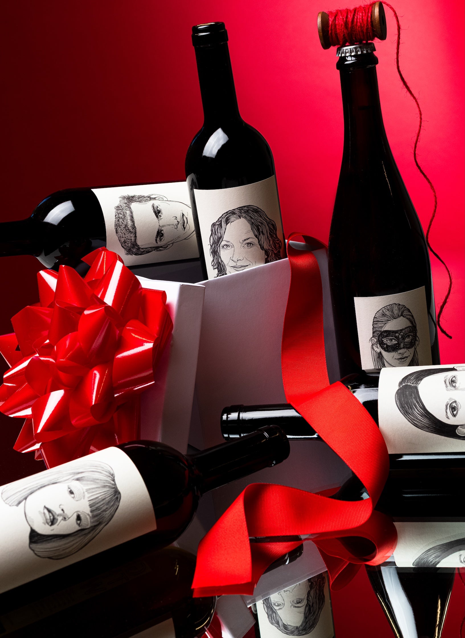 Gut Oggau natural wine bottles with illustrated labels in gift box with red ribbon on reflective surface for Mysa Natural Wine